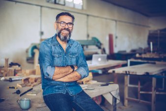 Carpenter smiling and leaning on table